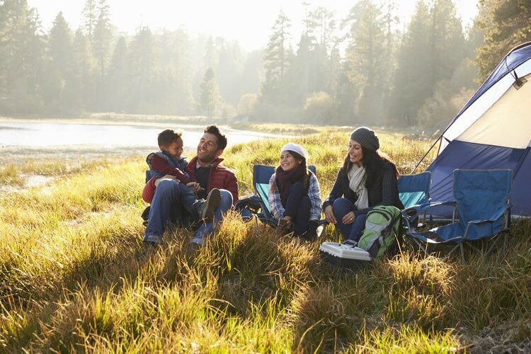 Family camping by lake wearing hats, coats and scarves