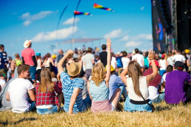 Young people sitting on a field enjoying an outdoor festival