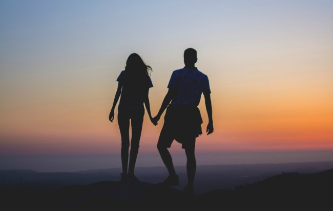 Romantic couple holding hands outdoors at sunset